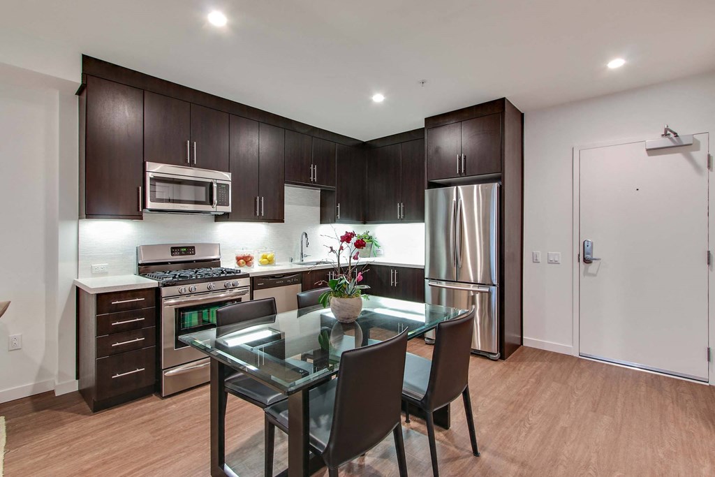 A modern kitchen with dark brown cabinets and stainless steel appliances.
