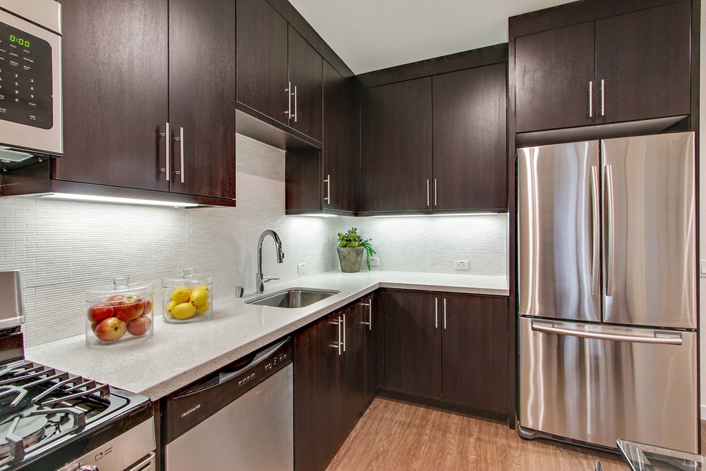 A kitchen with dark brown cabinets and a stainless steel refrigerator.