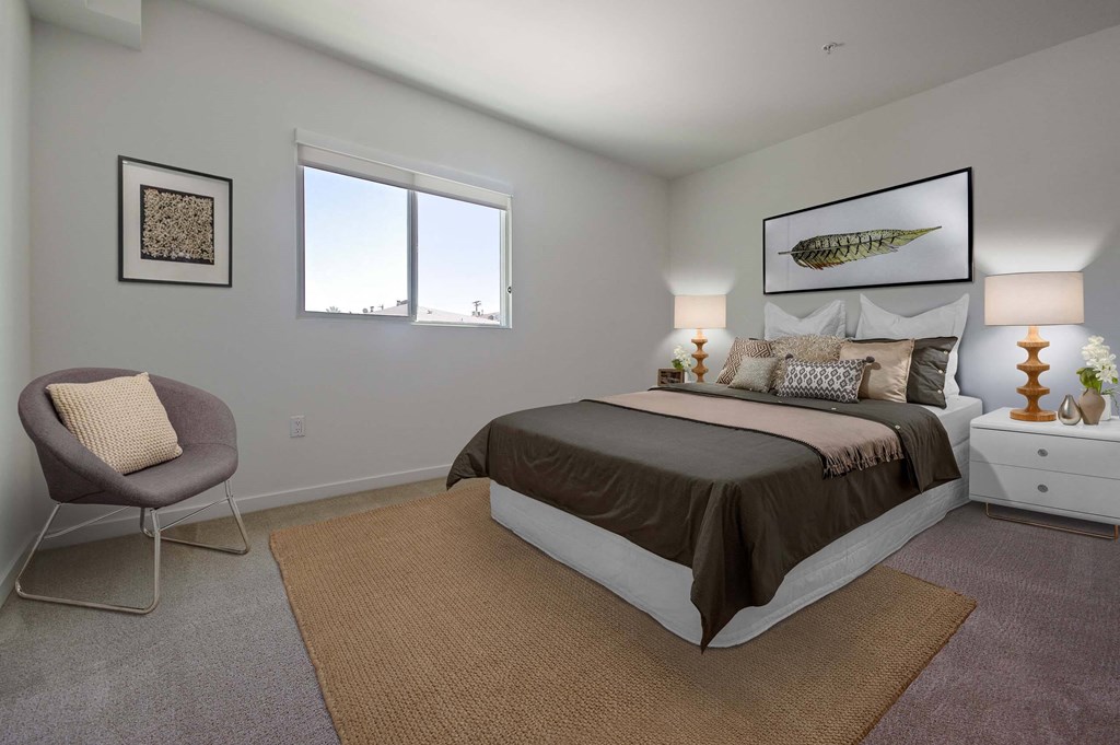A bedroom with a large bed, a chair, and a rug.