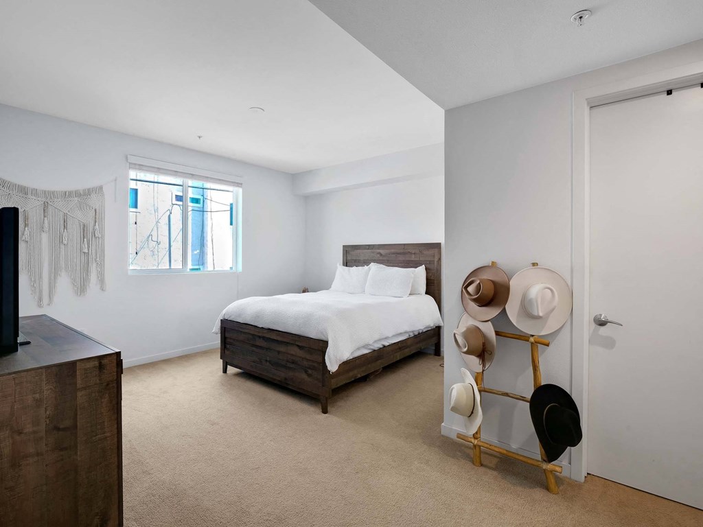 A bedroom with a bed, a hat rack, and a window.