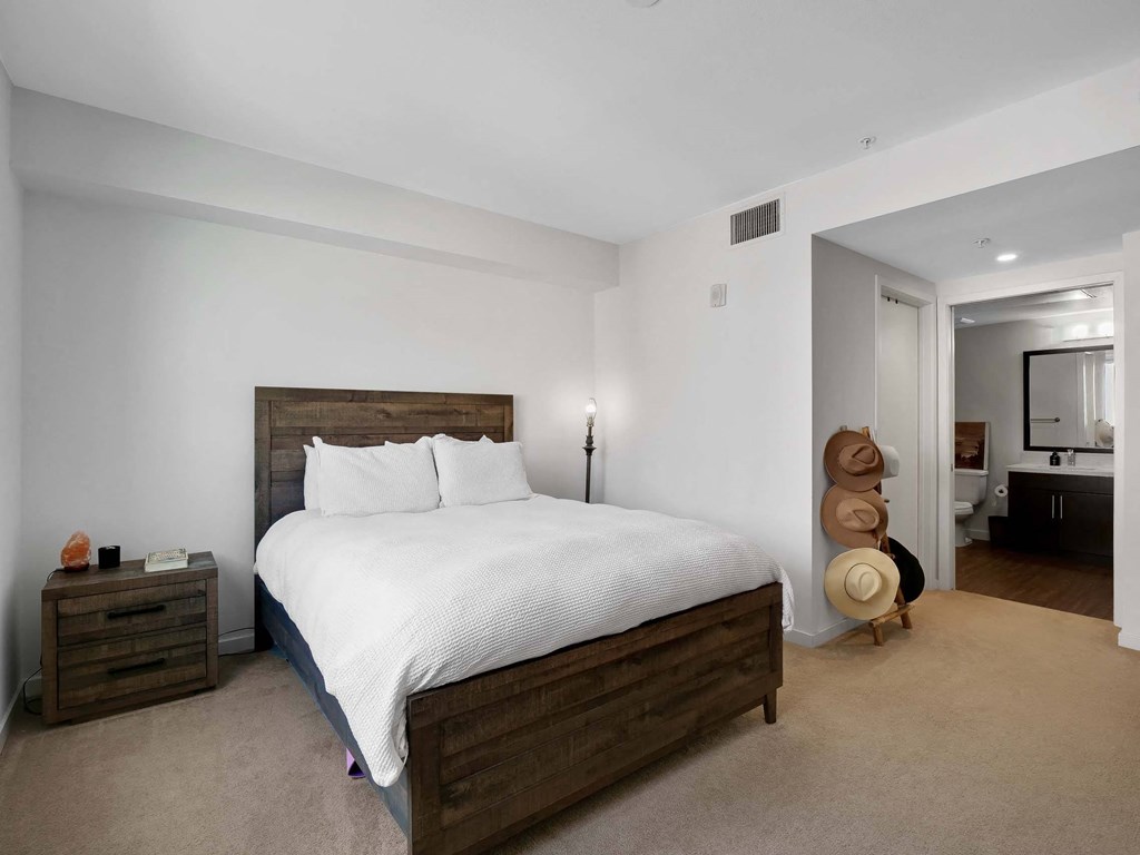 A bedroom with a large bed and a hat rack.