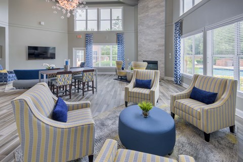 A living room with striped chairs and a round ottoman.