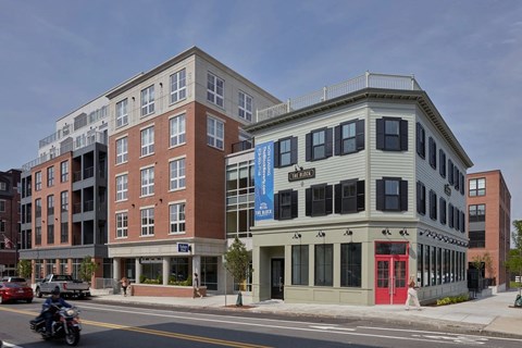 A motorcycle is on the road in front of a building with a red door.