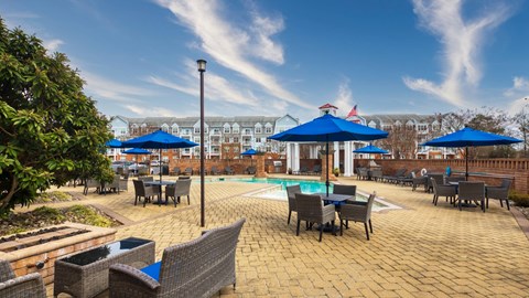 A patio with tables and chairs and umbrellas over them.