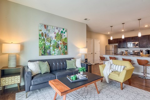 A living room with a grey couch and a painting on the wall.