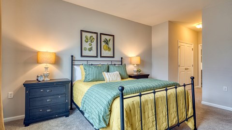 A bedroom with a bed, nightstand, and two wall lamps.