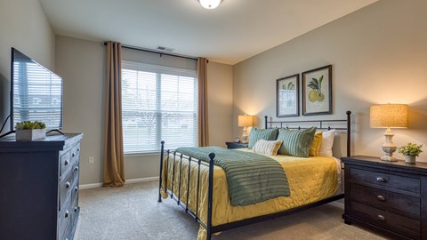 A bedroom with a bed, nightstand, and window.