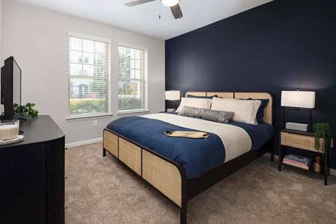 A bedroom with a bed, nightstand, and a ceiling fan.