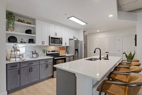 A modern kitchen with a white countertop and grey cabinets.