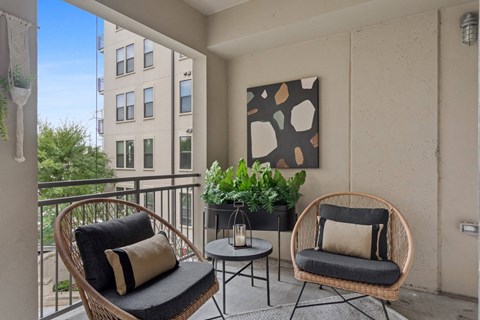 A balcony with two chairs and a table.