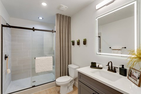 A bathroom with a white toilet, sink, and a glass shower door.