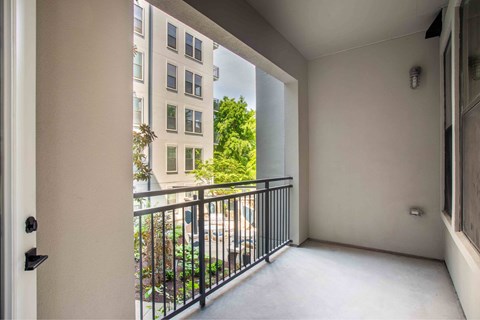 A balcony with a black railing and a view of a building and trees.
