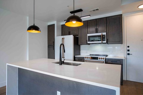 A modern kitchen with a white countertop and dark cabinets.