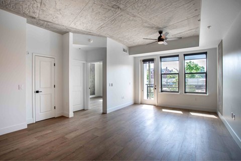 A room with a ceiling fan and a large window.