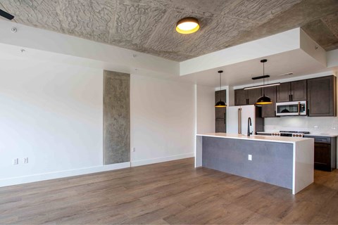 A modern kitchen with a wooden floor and a concrete island.