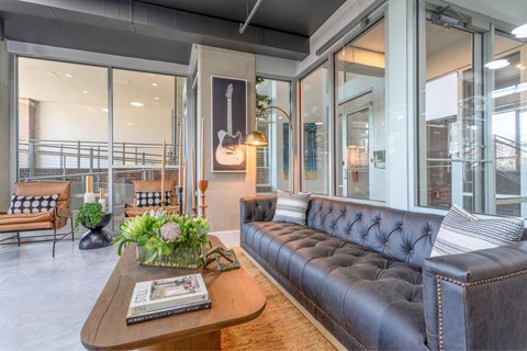 A living room with a black leather couch and a wooden coffee table.