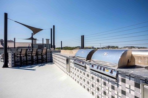 A row of outdoor grills are lined up on a patio.