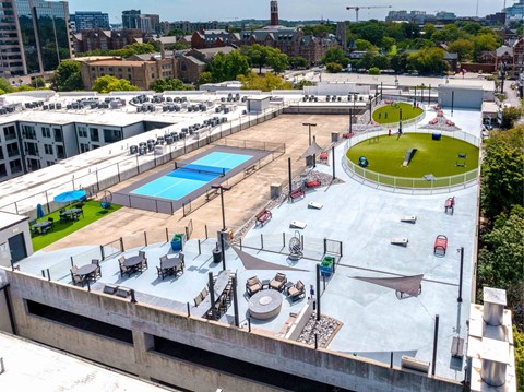 A rooftop with a pool, seating area, and a green space.