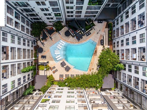 A swimming pool is surrounded by lounge chairs and umbrellas.
