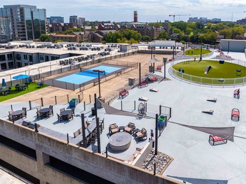 A rooftop with a pool, loungers, and a green space.