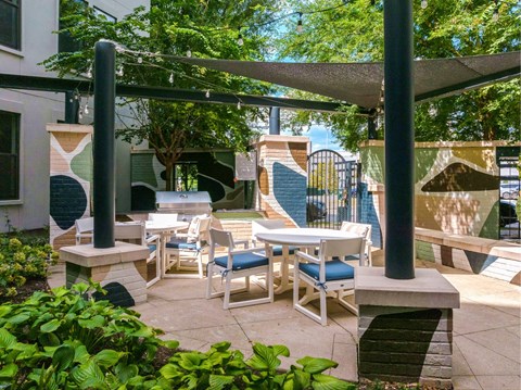 A patio with white chairs and tables under a canopy.