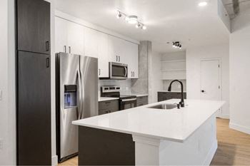 A modern kitchen with a white countertop and stainless steel appliances.