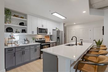 A modern kitchen with a white countertop and grey cabinets.