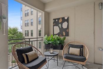 A balcony with two chairs and a table.