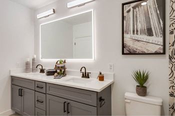 A bathroom with a vanity, toilet, and a framed picture on the wall.