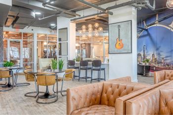 A room with brown leather couches and a guitar poster on the wall.