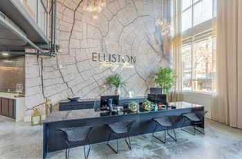 A reception area with a large table and chairs in front of a wall with a tree ring pattern and the word "ELLISON" on it.