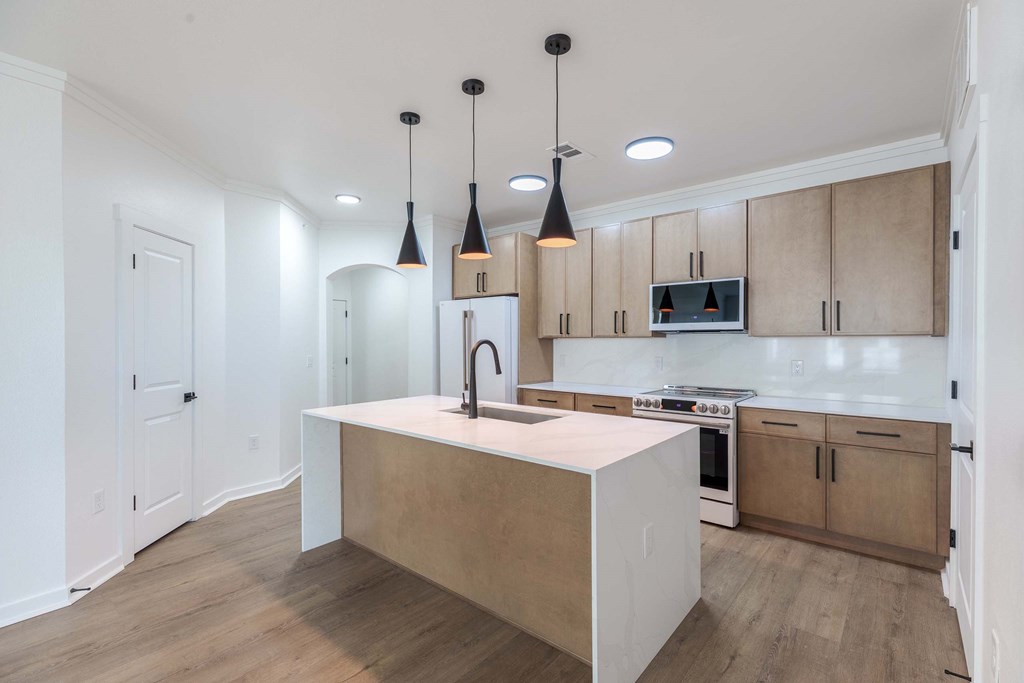 A kitchen with a white island and wooden cabinets.