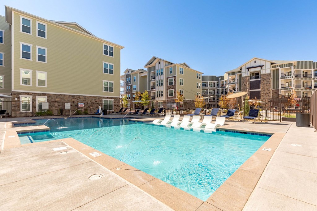 Five810 Southlands, Aurora, CO, Swimming Pool A swimming pool surrounded by lounge chairs and apartment buildings.