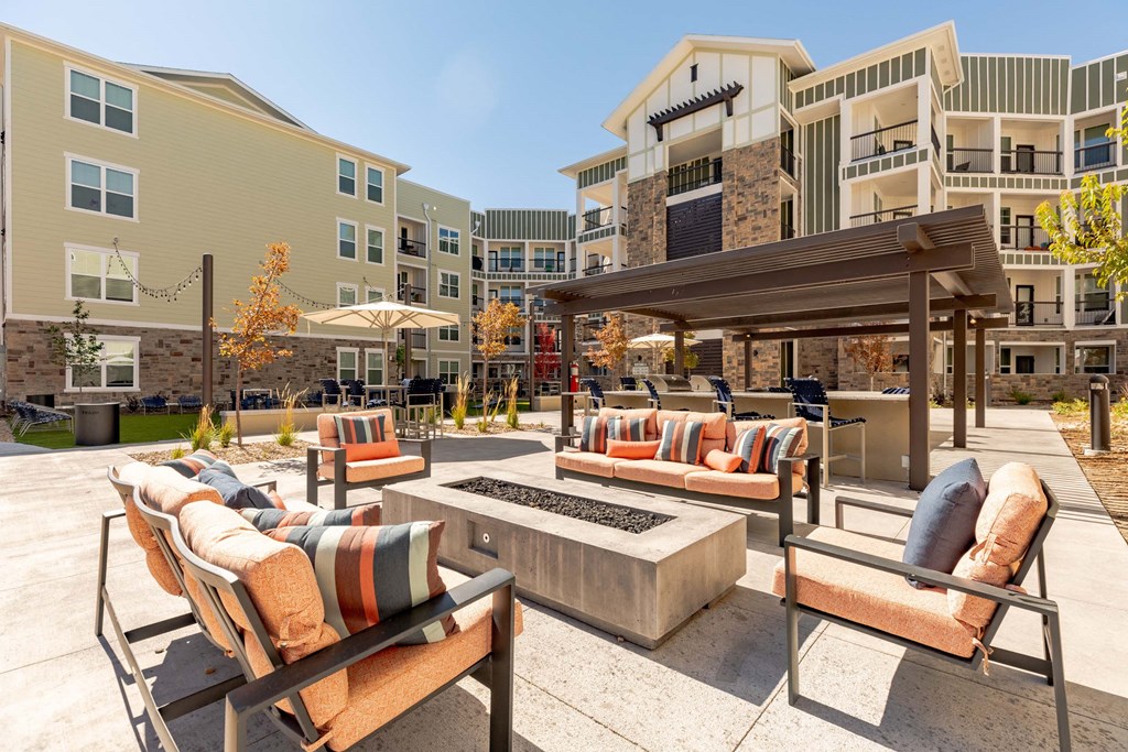 A patio with a fire pit and chairs.