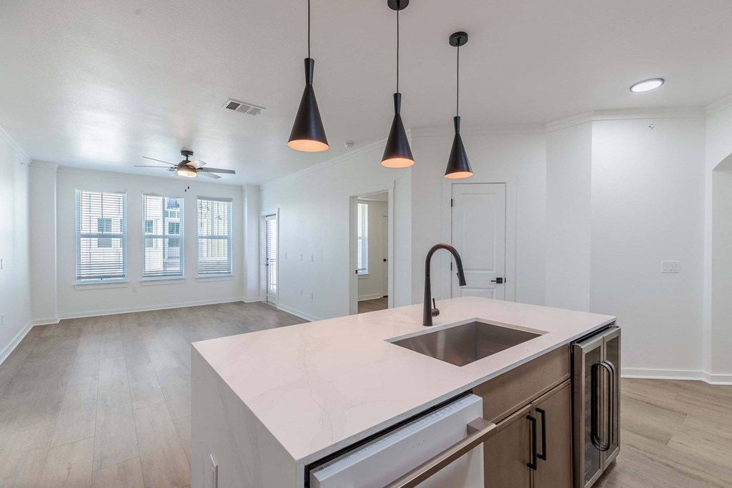A kitchen with a sink, stove, and a ceiling fan.