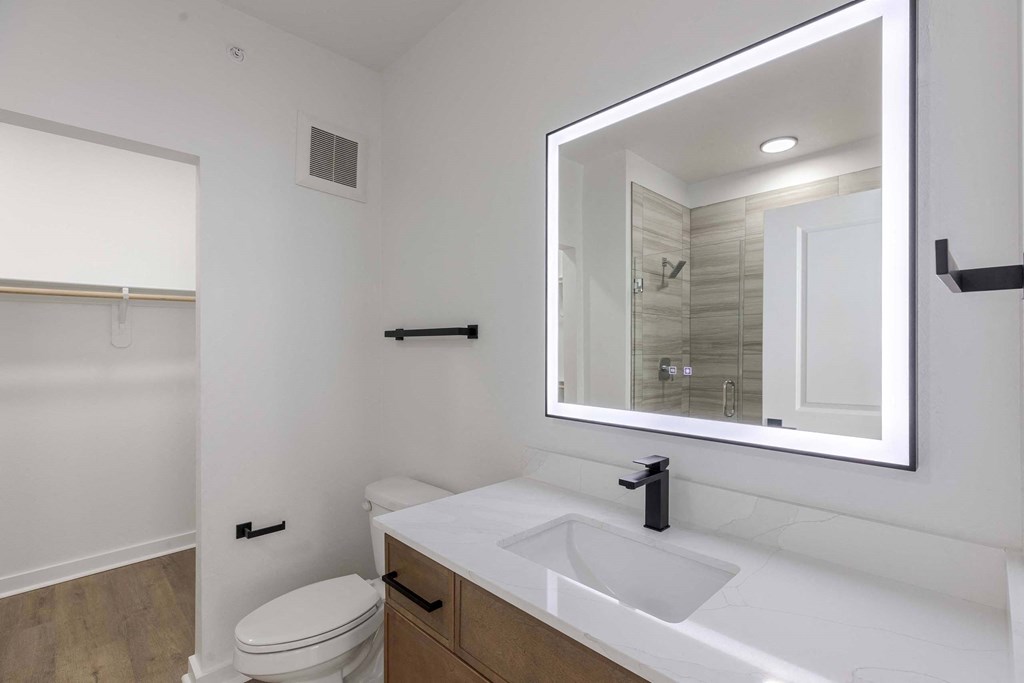A white bathroom with a toilet, sink, and mirror.