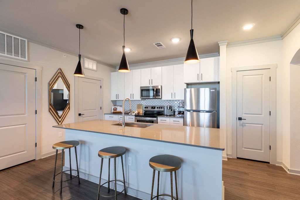 A kitchen with a white counter and bar stools.