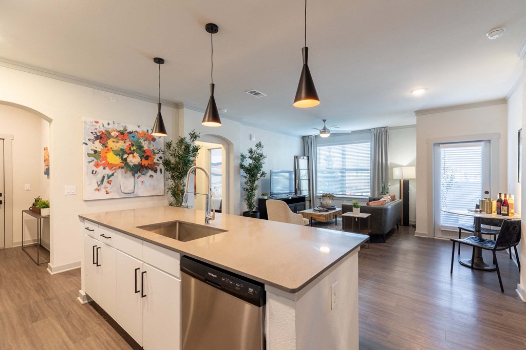 A modern kitchen with a large island and pendant lights.