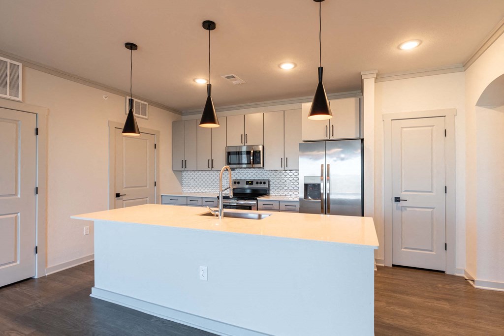 A kitchen with a white island and pendant lights.