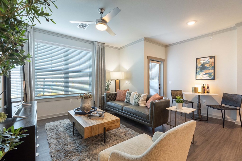 A living room with a brown couch, a coffee table, and a ceiling fan.