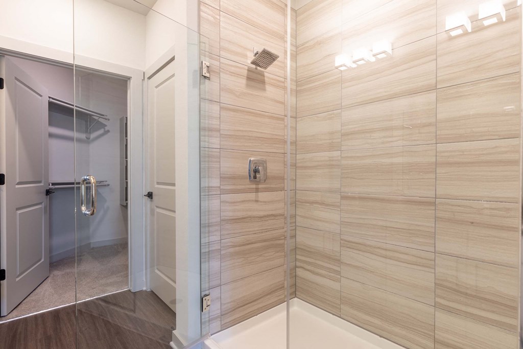A bathroom with a walk-in shower and a glass door.