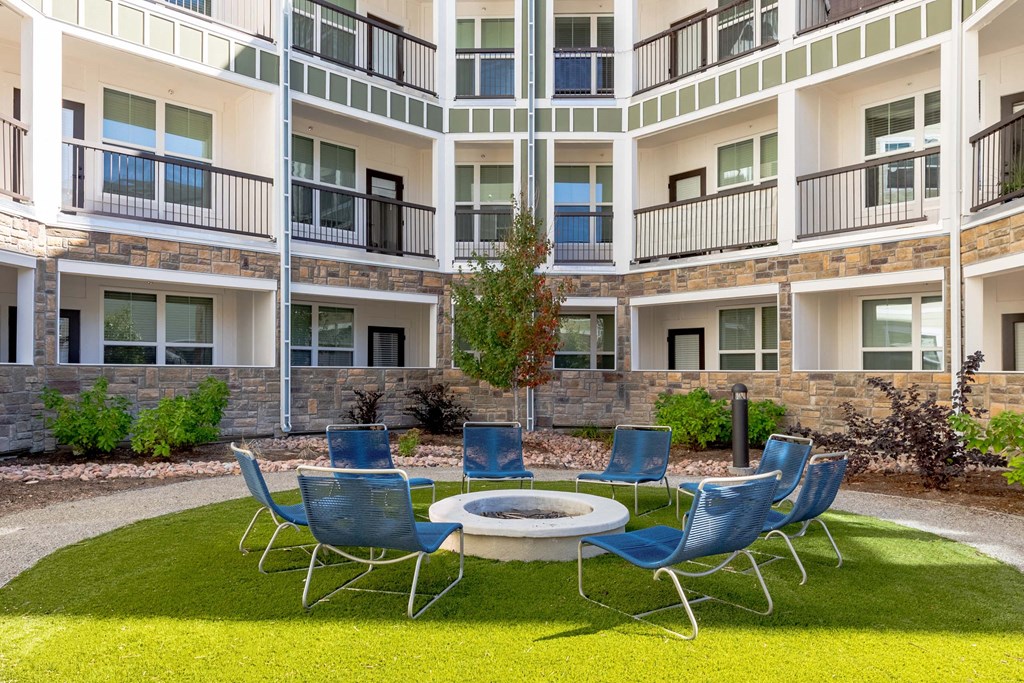 A small round table surrounded by blue chairs in front of a building.