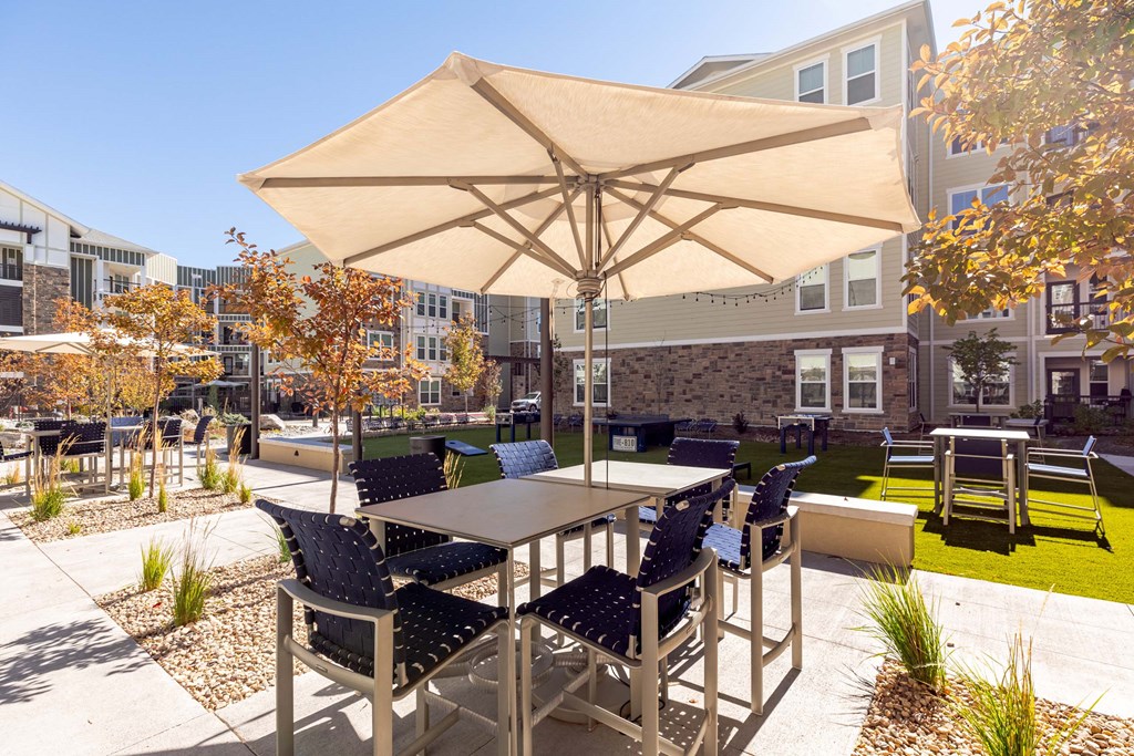 A patio with a table and chairs under an umbrella.