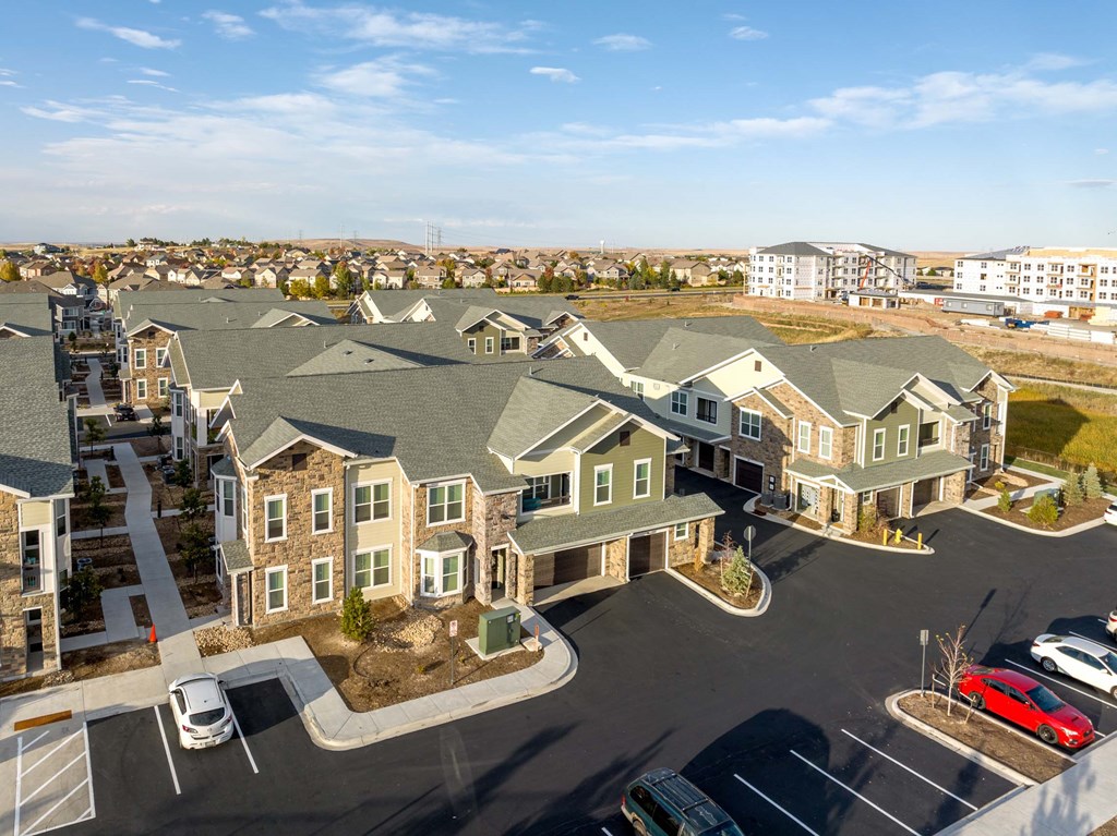 A large, modern building complex with a parking lot in front.