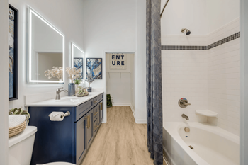 A bathroom with a blue vanity and a white bathtub.