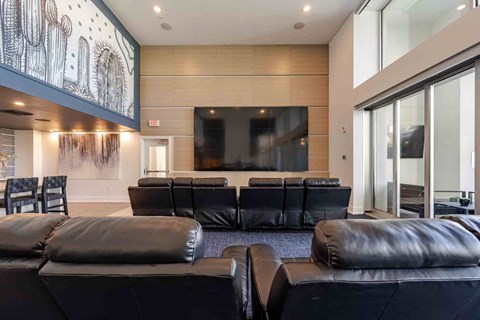 A modern living room with a large black leather sofa and a television.