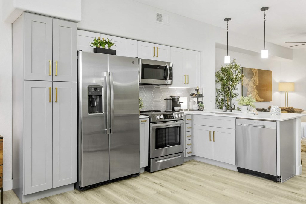A modern kitchen with a stainless steel refrigerator, microwave, and oven.