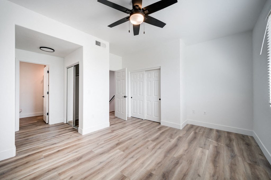A room with a ceiling fan and wooden flooring.