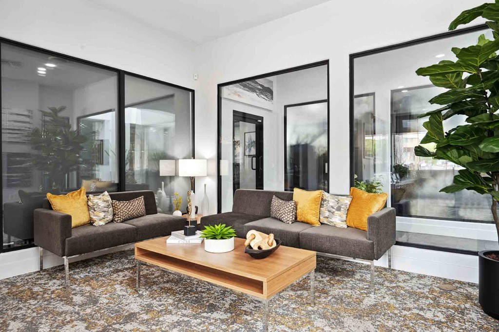 A living room with a grey couch, a wooden coffee table, and a large mirror on the wall.