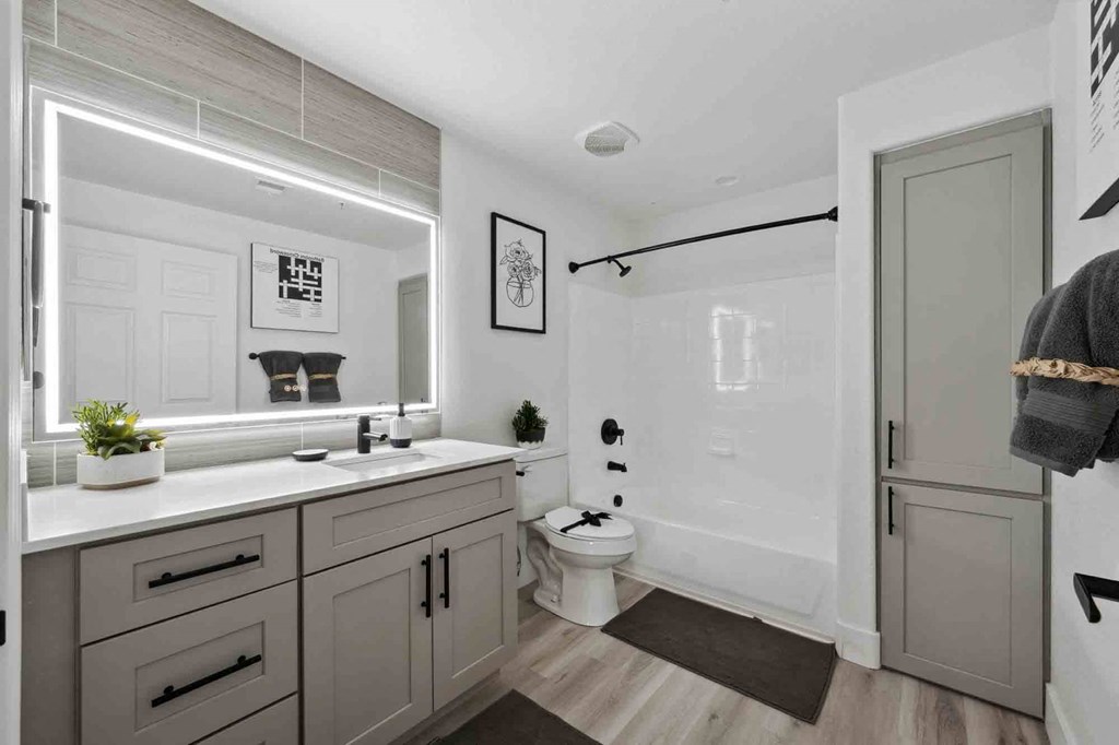 A bathroom with a white countertop and grey cabinets.